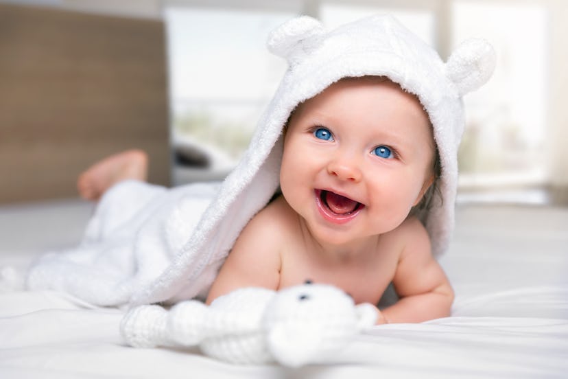 sweet little baby in a soft towel smiling at the camera in a round up of vintage baby names or old f...
