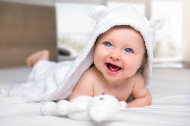 sweet little baby in a soft towel smiling at the camera in a round up of vintage baby names or old f...