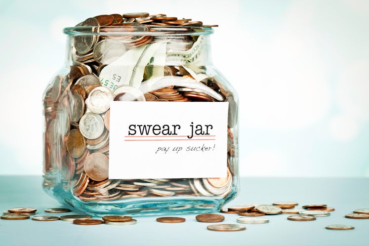Swear Jar shot against defocused background, overflowing with money collected.