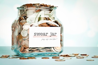 Swear Jar shot against defocused background, overflowing with money collected.