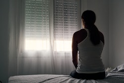 Rear view of an unrecognizable woman sitting on her bed  in an article about missed miscarriage and ...