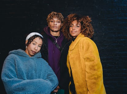 three friends smile for a photo in their winter coats as they discuss why november 2022 will be the ...