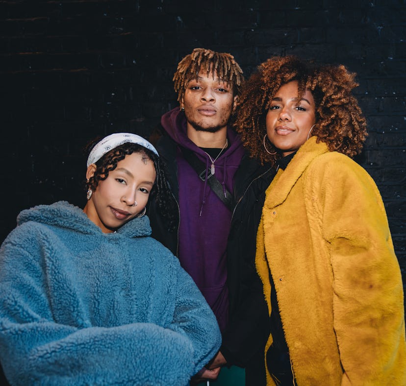 three friends smile for a photo in their winter coats as they discuss why november 2022 will be the ...