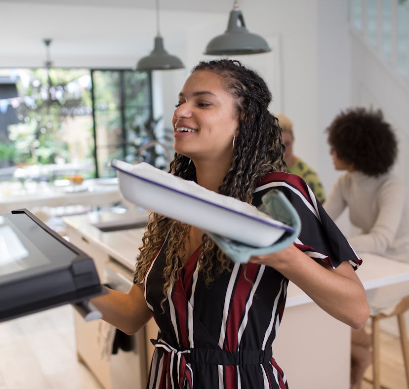 A woman places a dish in the oven after learning how to make TikTok's sushi bake recipe.