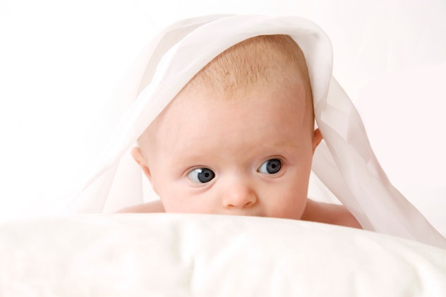Inquisitive 3 month old baby peering out from the covers in article about I girl names