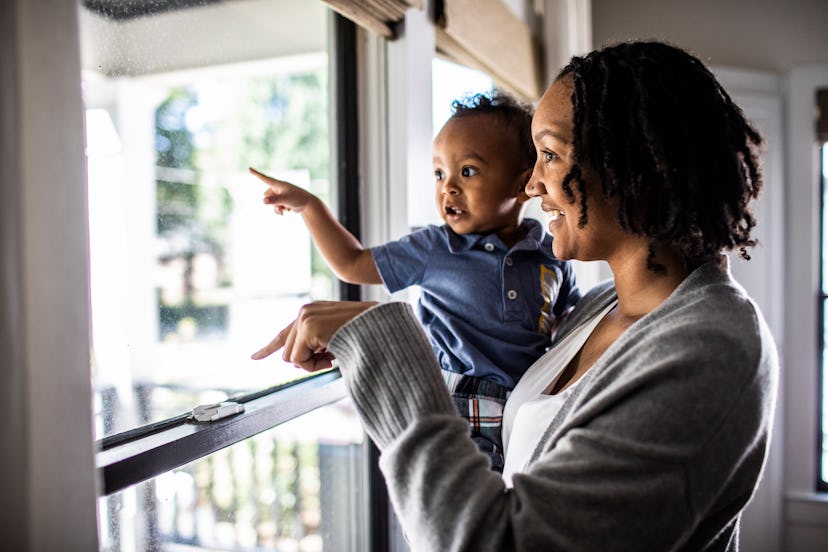 Mother and toddler looking out of home window in a round up of baby names that start with H
