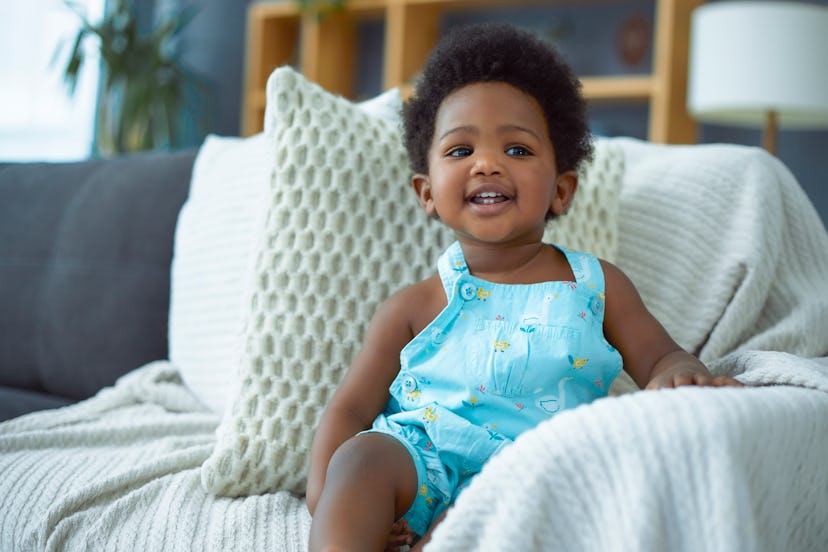 Happy toddler girl sitting in the sofa at home in article about girl names that start with I