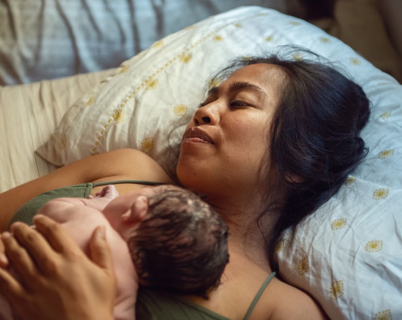 A woman who just experienced a home birth holds her just born baby in an article about birth plan ch...