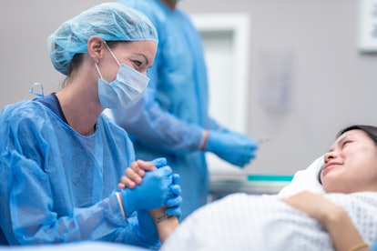 A female surgeon is with her team of surgeons, a group is preparing to perform a cesarian section on...