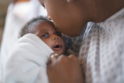 A young beautiful black mother is kissing her newborn son on the forehead. They are at the hospital....