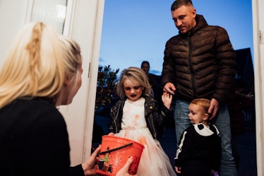 A brother and sister out trick or treating with their father, The little girl looks thrilled at the ...