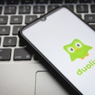 In this photo illustration a Duolingo logo seen displayed on a smartphone screen with a computer key...