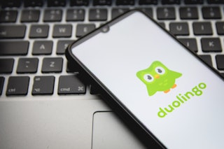 In this photo illustration a Duolingo logo seen displayed on a smartphone screen with a computer key...