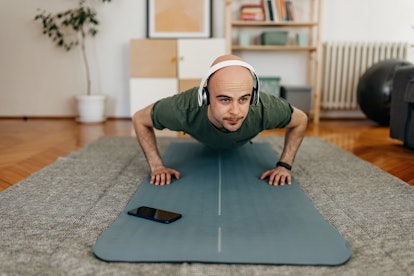 男人在家里的瑜伽垫上做俯卧撑。