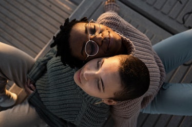 two women rest their heads on each other with their backs touching as they consider how their novemb...