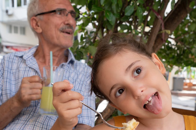 Grandpa and granddaughter eating cake together at cafe