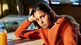 Young woman leaning on table during lunch break after reading her November 7, 2022 weekly horoscope.