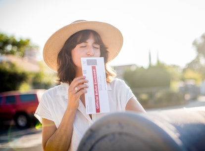 A young woman kisses her absentee voter ballot for the 2020 presidential election before she drops i...