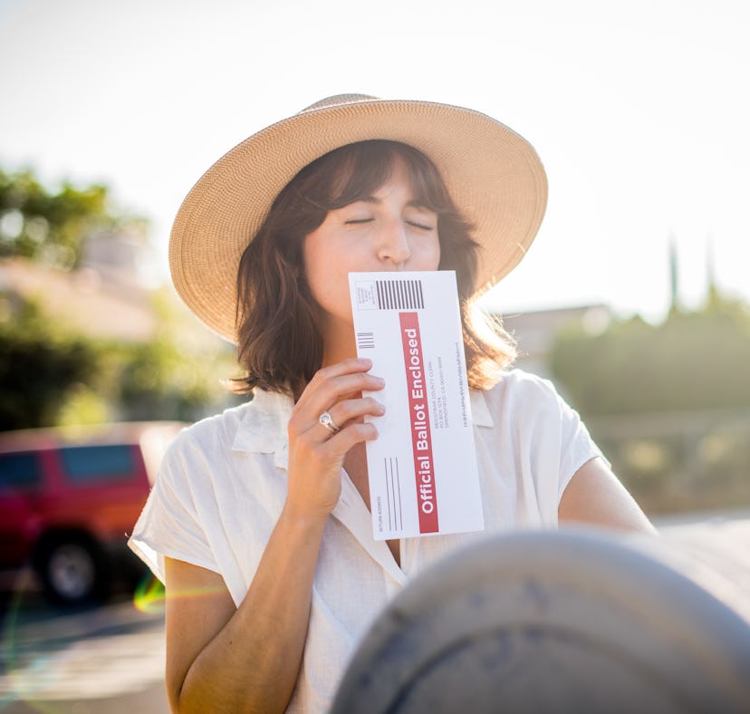 A young woman kisses her absentee voter ballot for the 2020 presidential election before she drops i...