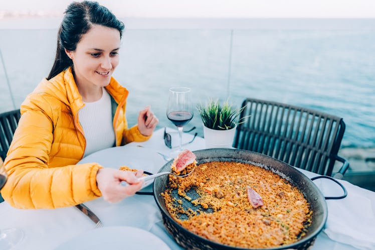 Happy tourist woman in restaurant ready to eat paella