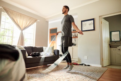 一名男子在客厅里跳绳，正在进行家庭锻炼。