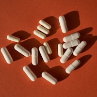Medicinal capsules on a terracotta background.