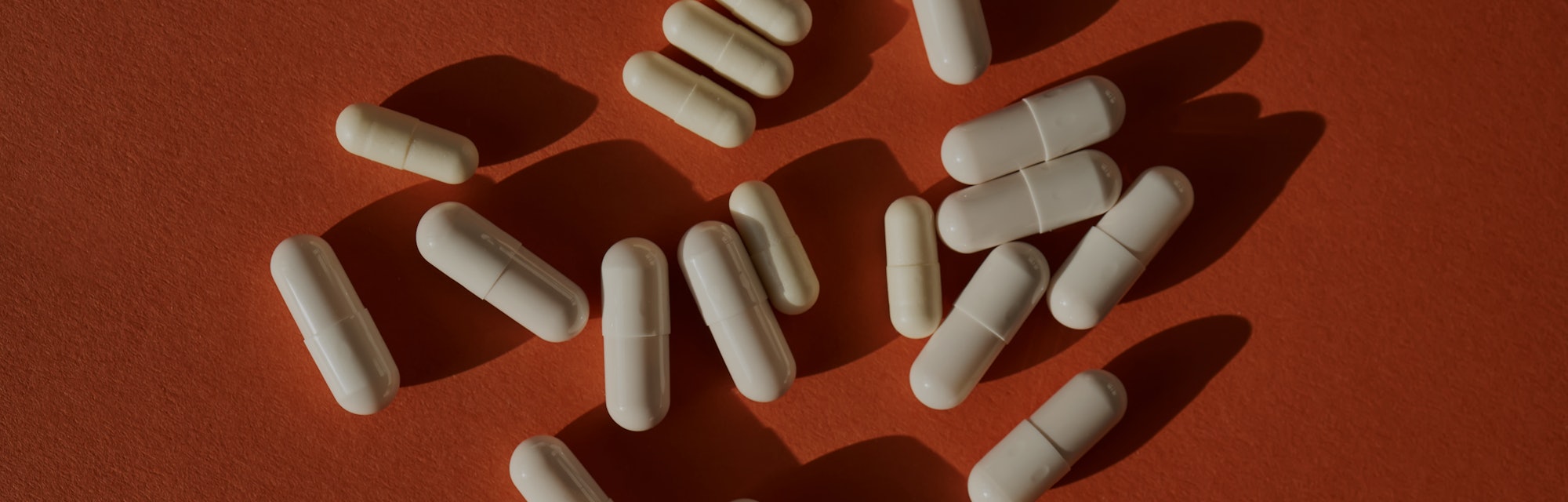 Medicinal capsules on a terracotta background.