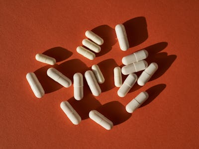 Medicinal capsules on a terracotta background.