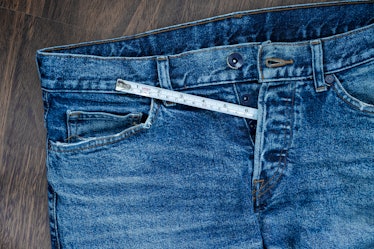 A tape measure sticking out of the fly of jeans at about the length of a penis.