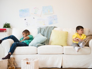 Two boys sitting on a couch, facing away from each other as one child is a bully
