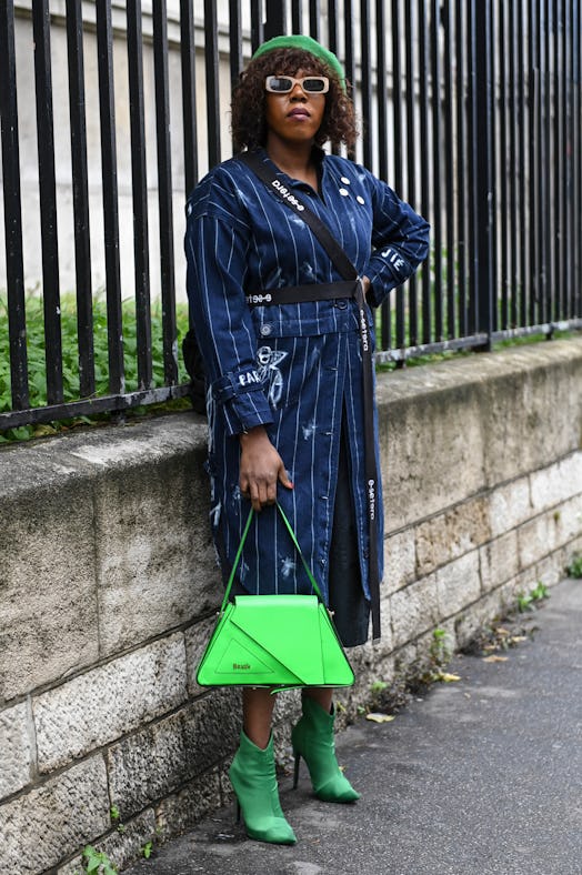 PARIS, FRANCE - OCTOBER 02: A guest is seen wearing a blue white striped coat, green hat, green bag ...