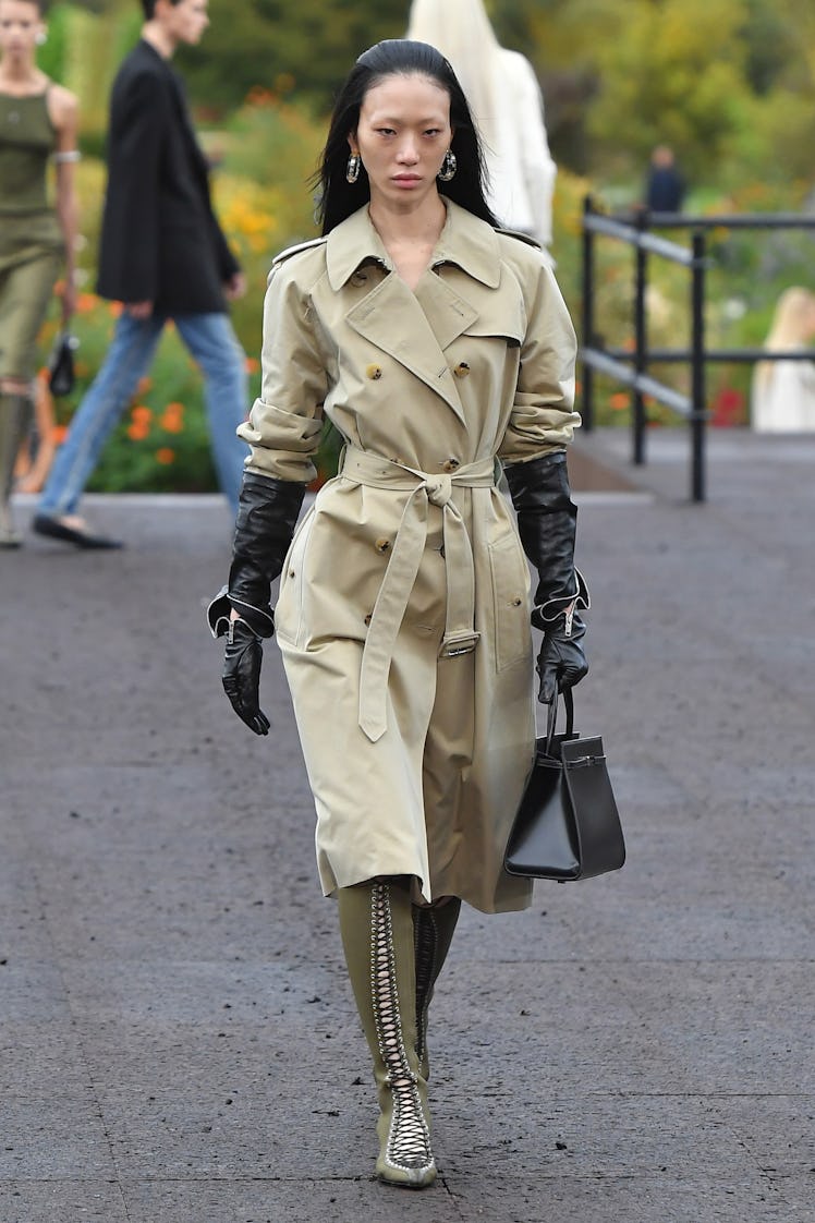 A model in Givenchy nude knee-high coat styled with black gloves and dark green lace boots at Paris ...