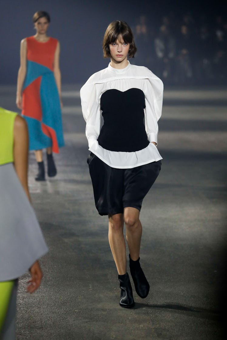 A model in Issey Miyake’s black shorts, and white oversize shirt with the black corset at Paris Fash...