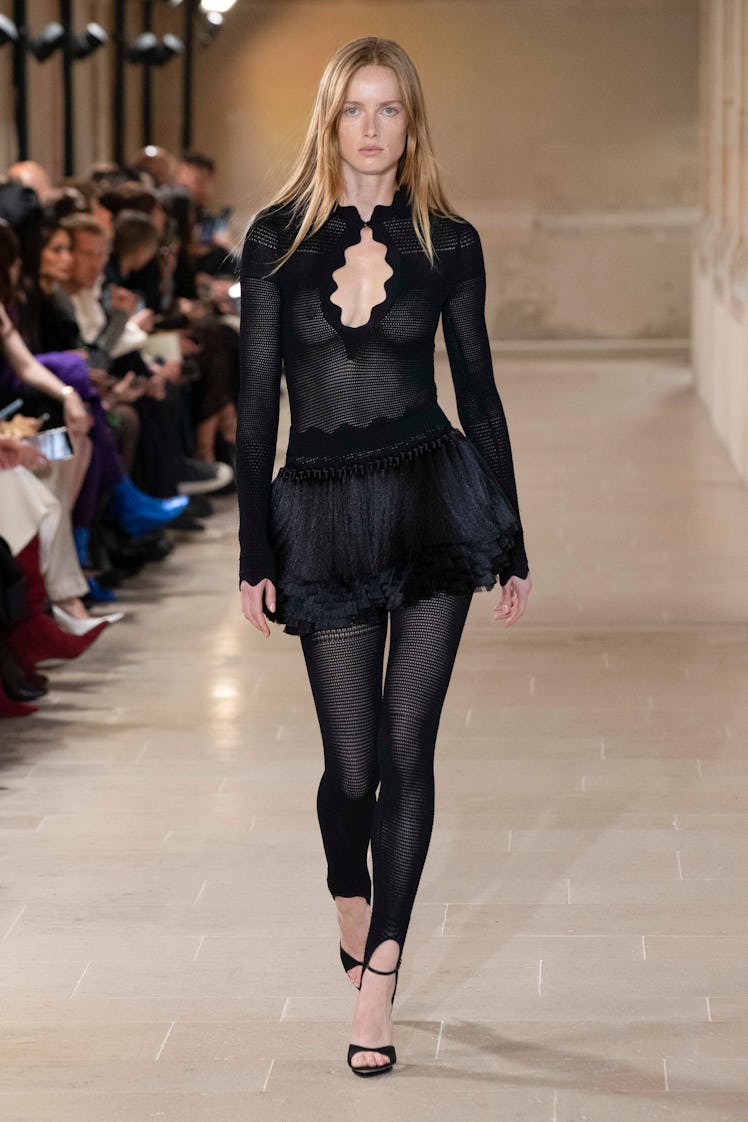 A model in Victoria Beckham black transparent jumpsuit and black mini skirt at Paris Fashion Week Sp...