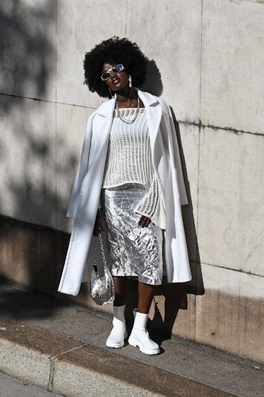 Wearing fall 2022 fashion trends for magenta auras, a guest is seen wearing a white coat, knit top, ...