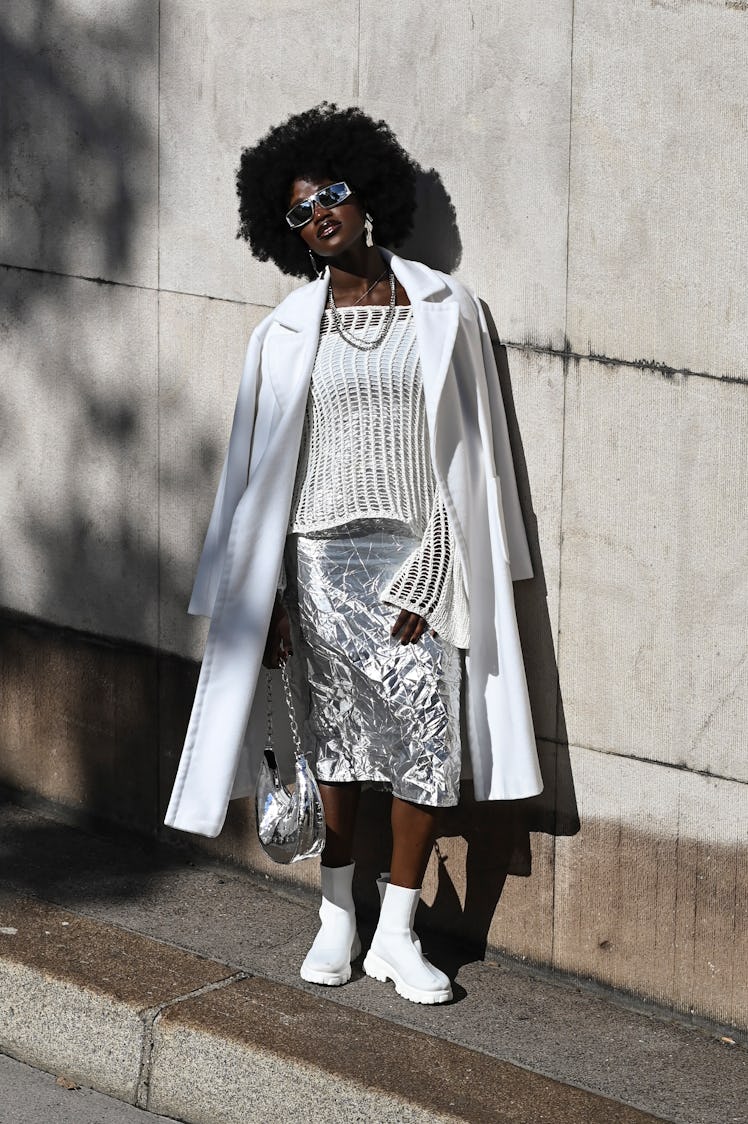 Wearing fall 2022 fashion trends for magenta auras, a guest is seen wearing a white coat, knit top, ...