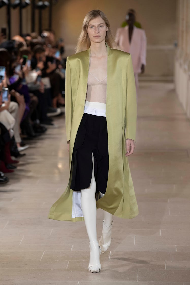 A model wearing Victoria Beckham’s long silk green blazer, nude shirt and black skirt at Paris Fashi...