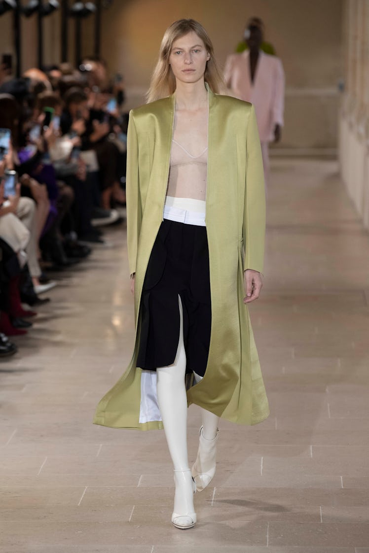 A model wearing Victoria Beckham’s long silk green blazer, nude shirt and black skirt at Paris Fashi...