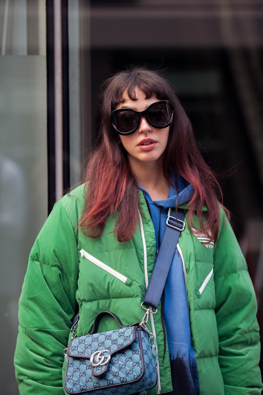 PARIS, FRANCE - SEPTEMBER 29: A guest wearing blur silk dress, blue and black sweater, green pyffy j...