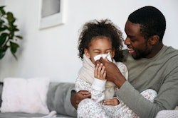 a father helps his daughter blow her nose. article about cough and cold medicines for kids.