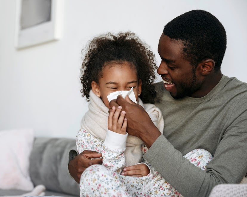 a father helps his daughter blow her nose. article about cough and cold medicines for kids.