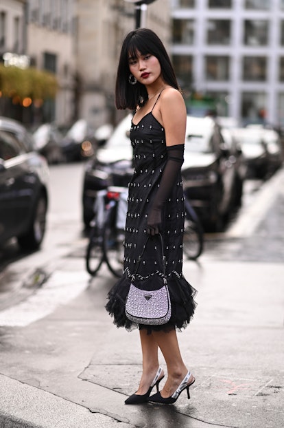 PARIS, FRANCE - SEPTEMBER 27: A guest is seen wearing a black beaded dress, sheer sleeves, Prada bag...