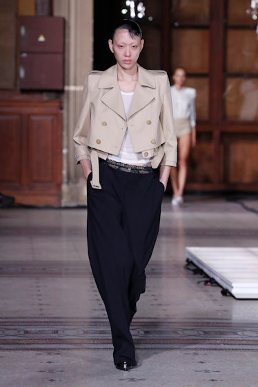 A model wearing Coperni nude short blazer, white plain t-shirt, and long black pants at Paris Fashio...