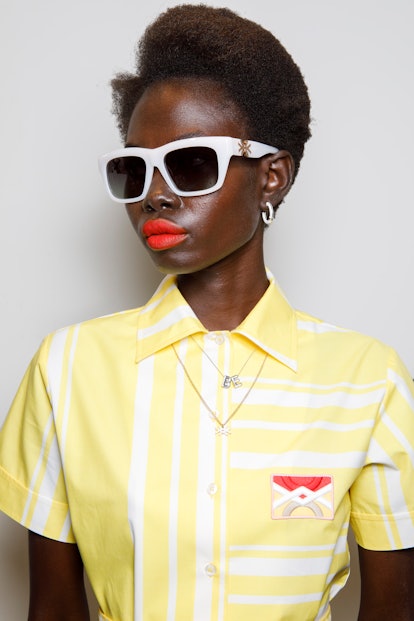  A model with a bold lip, the 2022 holiday beauty trend for Gemini, poses backstage at the Benetton ...