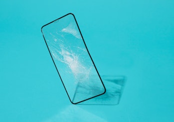 a broken smartphone screen protector standing on a blue background