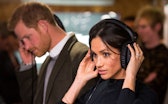 Britain's Prince Harry and his fiancée US actress Meghan Markle listen to a broadcast through headph...