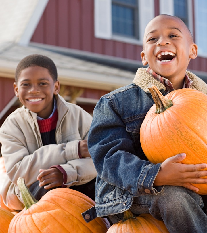 little boy holding a pumpkin at a pumpkin patch in a round up of pumpkin caption ideas