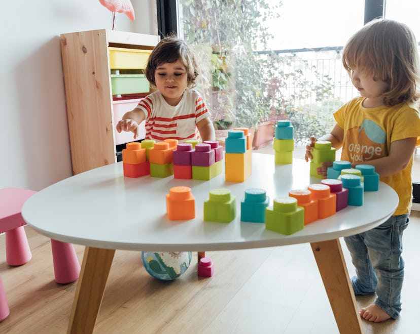 2-year-old little boy and girl playing with colorful plastic toy blocks