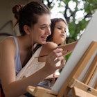 Young woman with her daughter painting on easel.