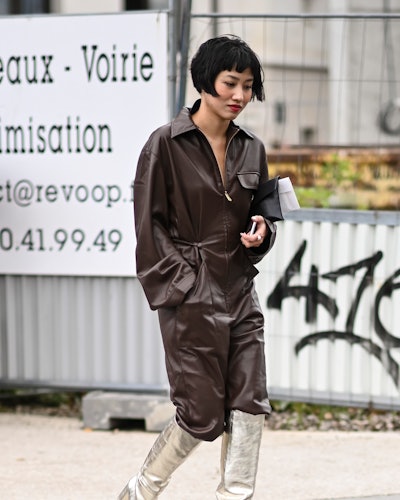 A guest is seen wearing a brown leather jumpsuit and gold boots